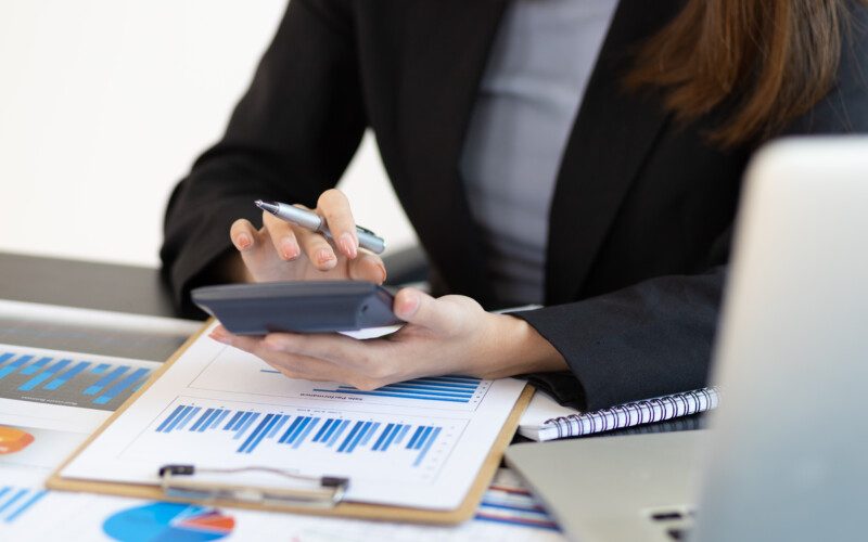 Financial planning and expense accounting concepts. Businesswoman analyzing a business account report using a calculator.