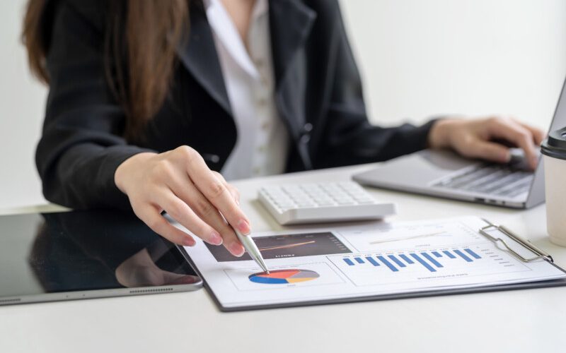 Close-up of a businesswoman hand holding a pen pointing at a chart statistical analysis sitting at the office.